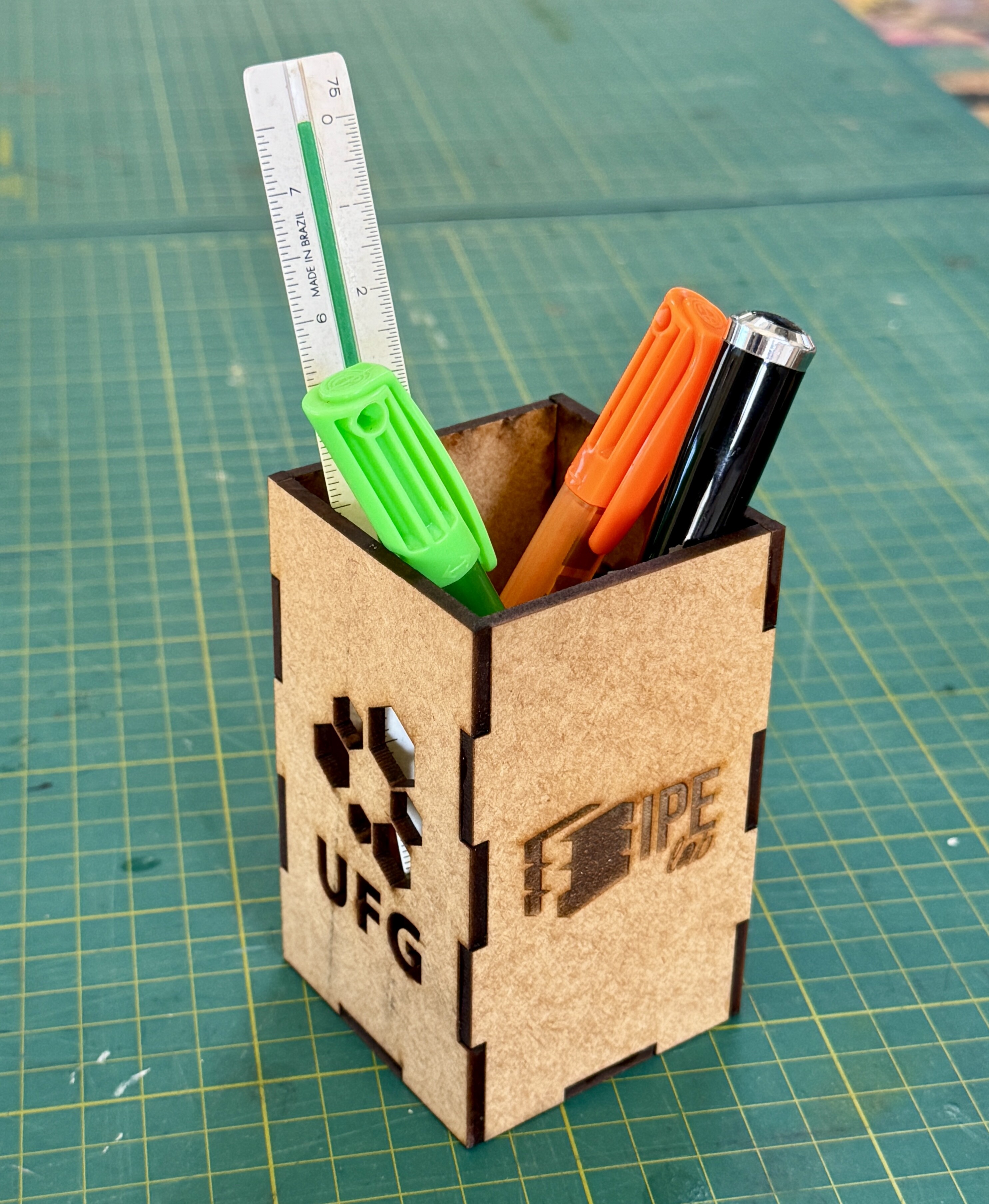 Foto do porta-canetas de MDF finalizado, com canetas e régua dentro dele, demonstrando como pode ser usado.