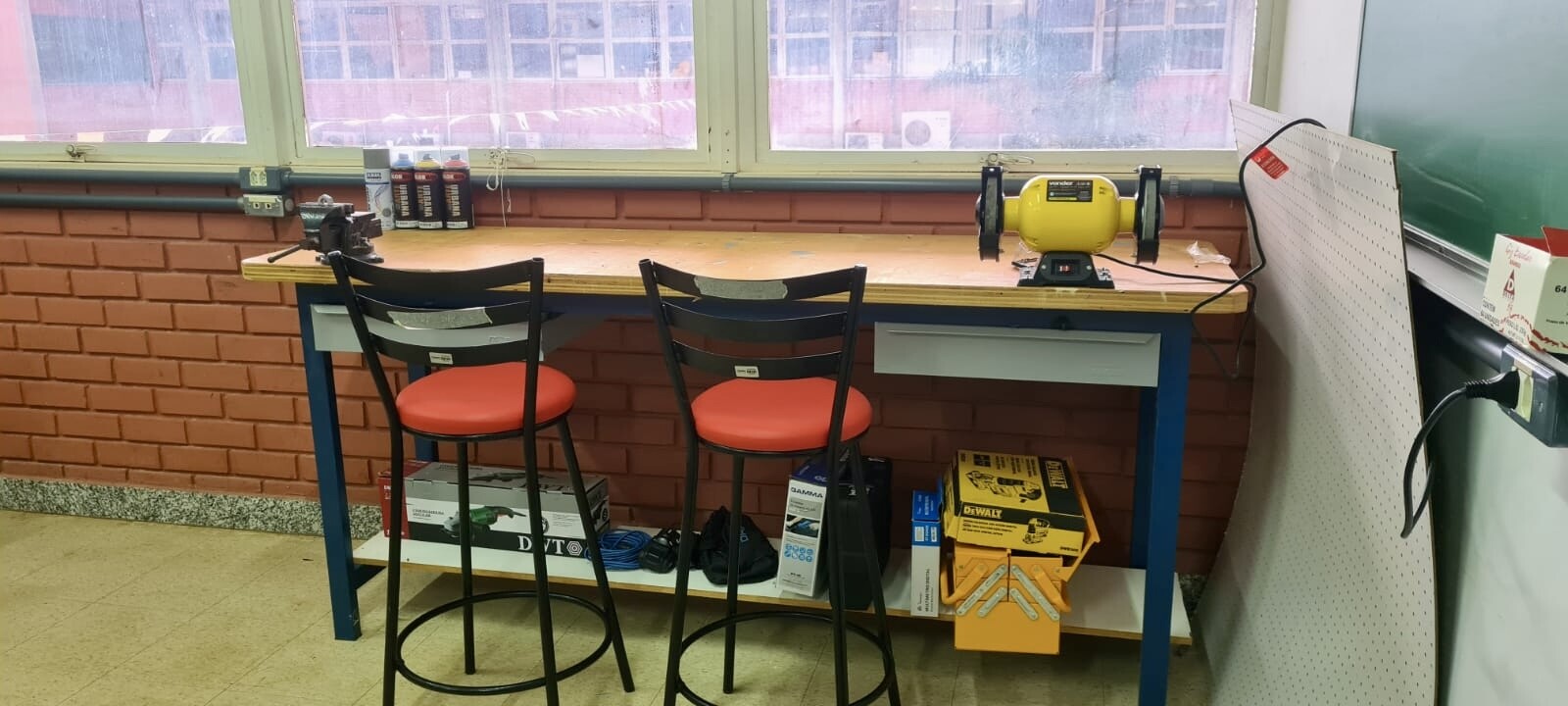 Foto no IPElab Física de ferramentas sobre uma bancada, e duas cadeiras em frente a bancada.