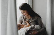 Imagem mostra mulher amamentando seu bebê por trás de uma cortina