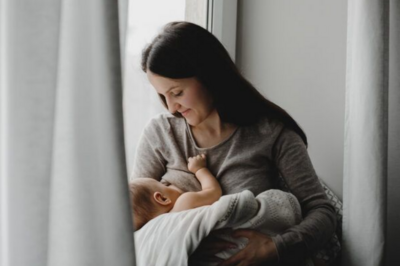Imagem mostra mulher amamentando seu bebê por trás de uma cortina