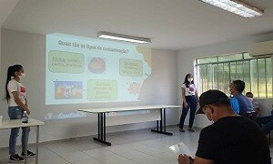 Acadêmicas do curso de Nutrição ministrando palestra sobre Boas Práticas de Fabricação aos agricultores locais no Campus Firminópolis, como atividade proposta pelo Estágio Comunitário Interprofissional.