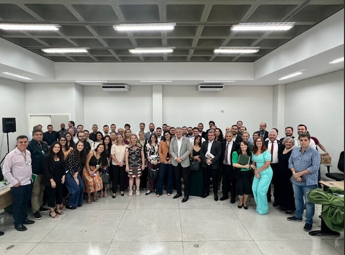 Foto dos representantes instituições Fórum Goiano de Governo Aberto. Sala ampla, grande quantidade de pessoas posando para a foto. 