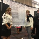 Foto das Professoras Márcia Maria de Souza e Sheila Araújo Teles em frente à Poster contendo resultado de pesquisa. 