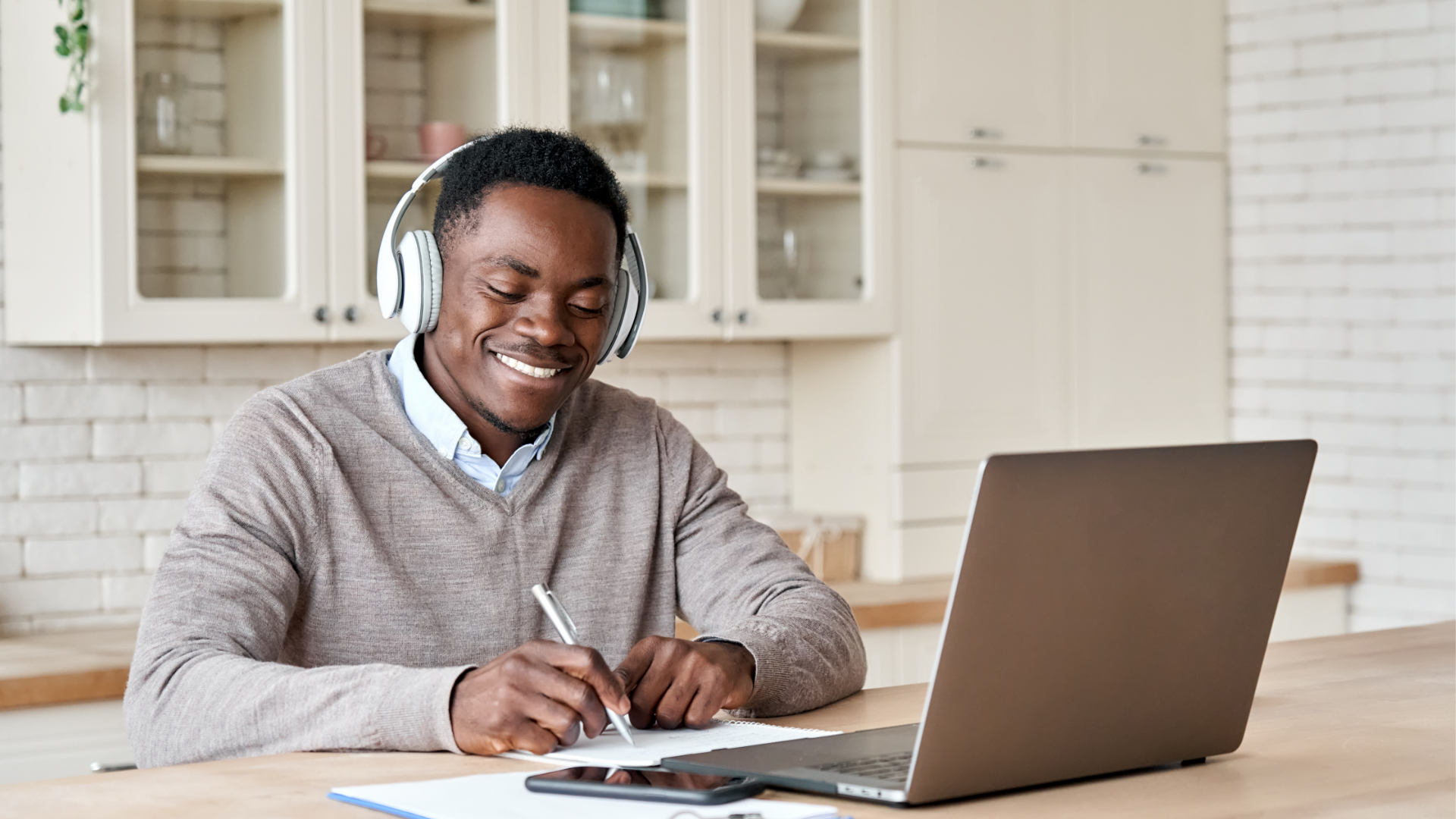 Foto notícia 120324. Na imagem, homem negro está sentado à mesa, com fones de ouvido e à frente de um computador, levando a entender que ele está estudando. 