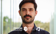 tese_premiada_Daniel_Albuquerque
#ParaTodosVerem 
Homem jovem, de pele clara, com cabelos curtos e escuros e barba, está centralizado na imagem, olhando diretamente para a câmera com expressão neutra. Ele veste uma camisa escura. Ao fundo, há um ambiente com iluminação natural e elementos desfocados em tons claros e verdes. Na parte inferior da imagem, aparecem os logotipos do PPGIDH (Programa de Pós-Graduação Interdisciplinar em Direitos Humanos), do NDH (Núcleo Interdisciplinar de Pesquisa, Ensino e Extensão em Direitos Humanos) e da UFG (Universidade Federal de Goiás).