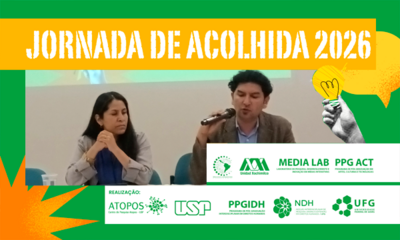 #PraTodosVerem: Banner horizontal com bordas verdes. No topo, uma faixa amarela destaca o título em letras brancas: "JORNADA DE ACOLHIDA 2026". Ao centro, uma fotografia mostra um homem falando ao microfone ao lado de uma mulher; ambos estão sentados em uma mesa de evento. À direita da foto, há uma colagem ilustrativa de uma mão em preto e branco segurando uma lâmpada amarela acesa. Há grafismos como um balão de fala amarelo à direita e uma estrela geométrica laranja no canto inferior esquerdo. Na parte inferior e sobrepostas à direita, faixas brancas contêm os logotipos das instituições organizadoras e parceiras, incluindo USP, UFG, Atopos, Media Lab, PPGIDH, NDH, PPG ACT e Unidad Xochimilco.