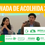 #PraTodosVerem: Banner horizontal com bordas verdes. No topo, uma faixa amarela destaca o título em letras brancas: "JORNADA DE ACOLHIDA 2026". Ao centro, uma fotografia mostra um homem falando ao microfone ao lado de uma mulher; ambos estão sentados em uma mesa de evento. À direita da foto, há uma colagem ilustrativa de uma mão em preto e branco segurando uma lâmpada amarela acesa. Há grafismos como um balão de fala amarelo à direita e uma estrela geométrica laranja no canto inferior esquerdo. Na parte inferior e sobrepostas à direita, faixas brancas contêm os logotipos das instituições organizadoras e parceiras, incluindo USP, UFG, Atopos, Media Lab, PPGIDH, NDH, PPG ACT e Unidad Xochimilco.