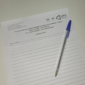 Foto em que aparece o cabeçalho de uma prova de processo seletivo da DAC com uma caneta em cima.