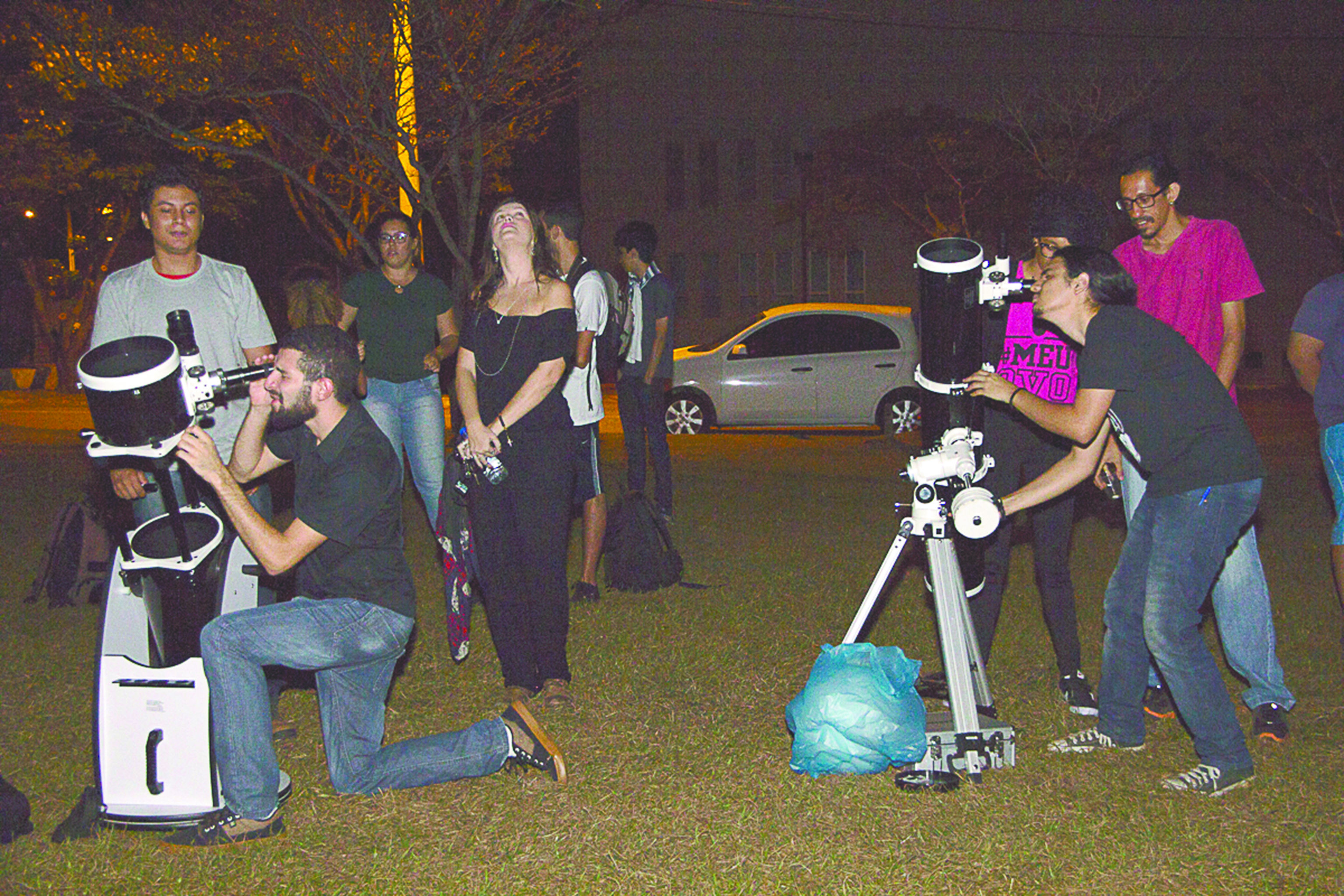 Pessoas em campo observando os astros através dos instrumentos