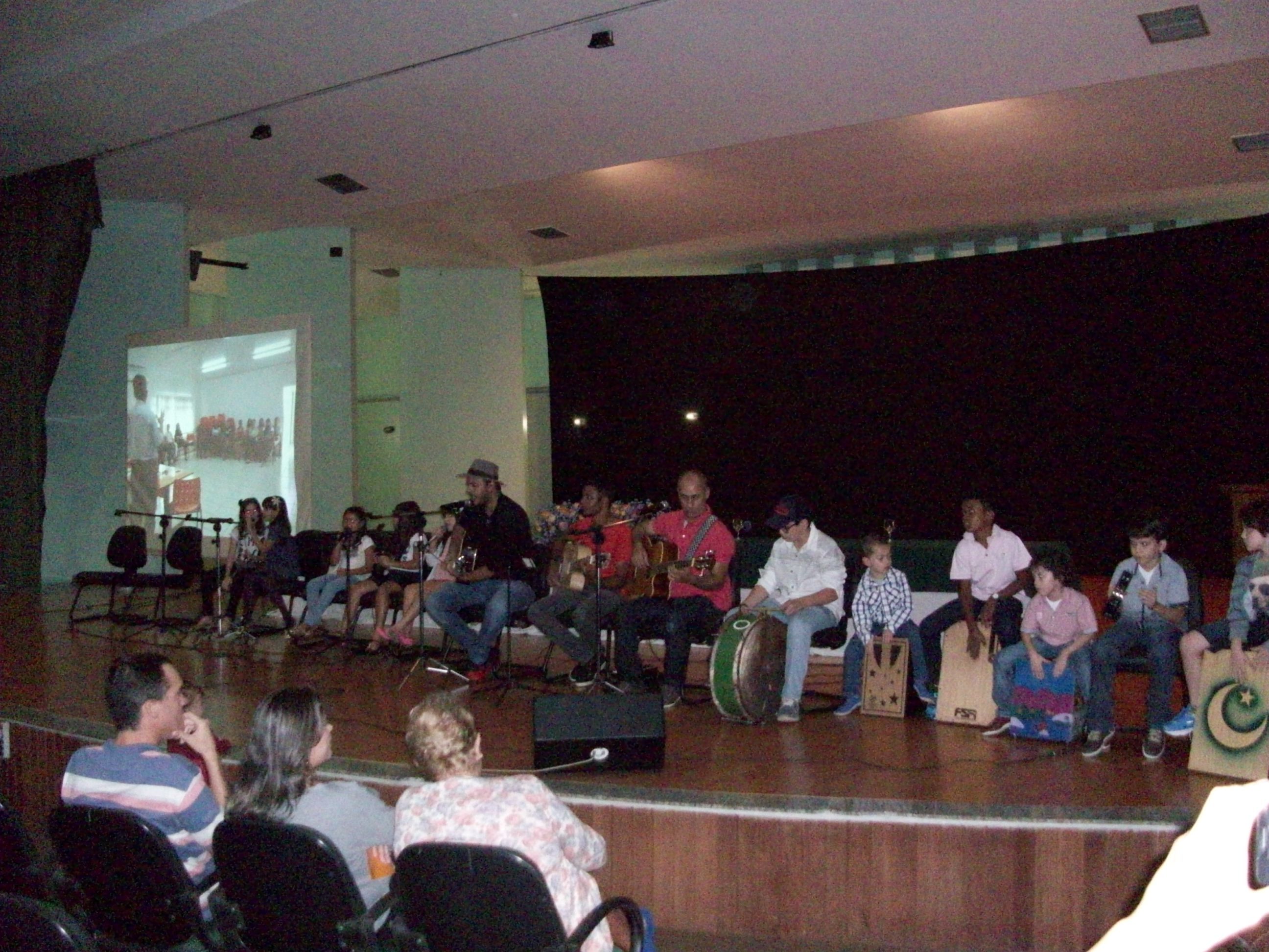 Tio Henrique no palco com as crianças cantando uma musica e tocando os instrumentos 