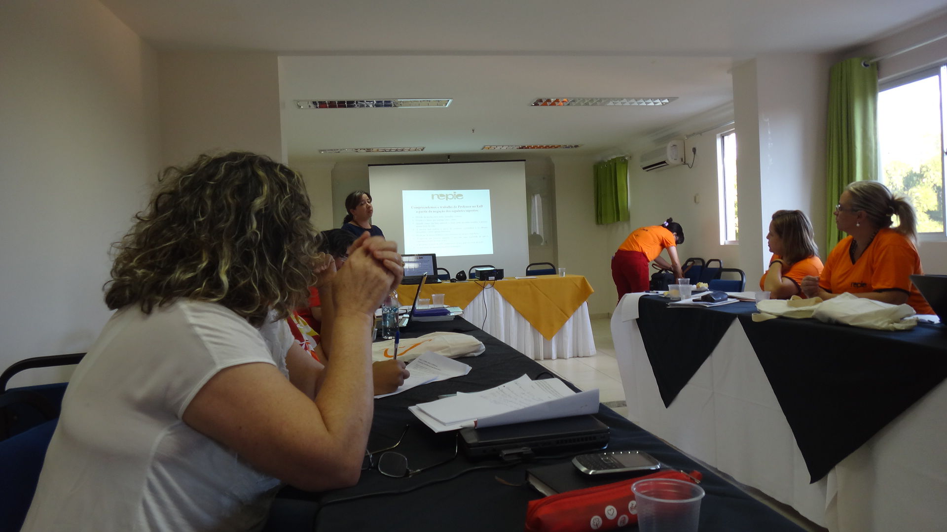 PESSOAS SENTADAS PRESTANDO ATENÇÃO NA APRESENTAÇÃO 