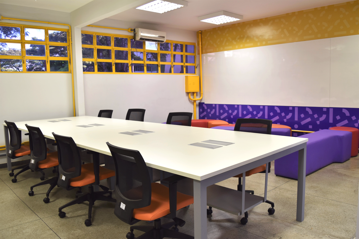 Espaço de coworking do CEI/UFG com mesa compartilhada, cadeiras e área de convivência