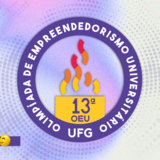 O banner apresenta o logotipo da 13ª Olimpíada de Empreendedorismo Universitário da UFG sobre um fundo abstrato em tons de lilás e branco. O emblema central é circular e roxo, contendo uma chama estilizada colorida e a identificação do evento. Elementos gráficos tridimensionais, como foguetes, lâmpadas e emojis sorridentes, decoram as extremidades da imagem, reforçando uma estética dinâmica e criativa.