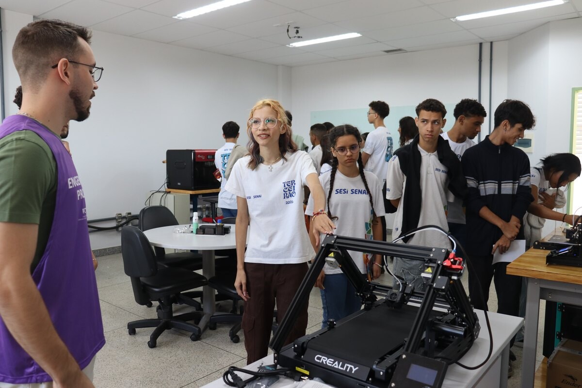 Estudantes diante de impressora 3D na Engenharia de Produção