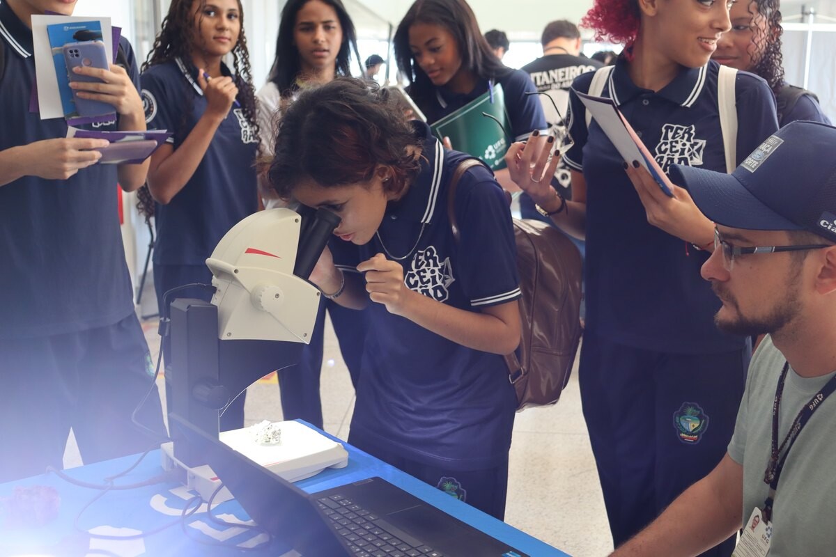 Estudante observa amostra em equipamento de laboratório